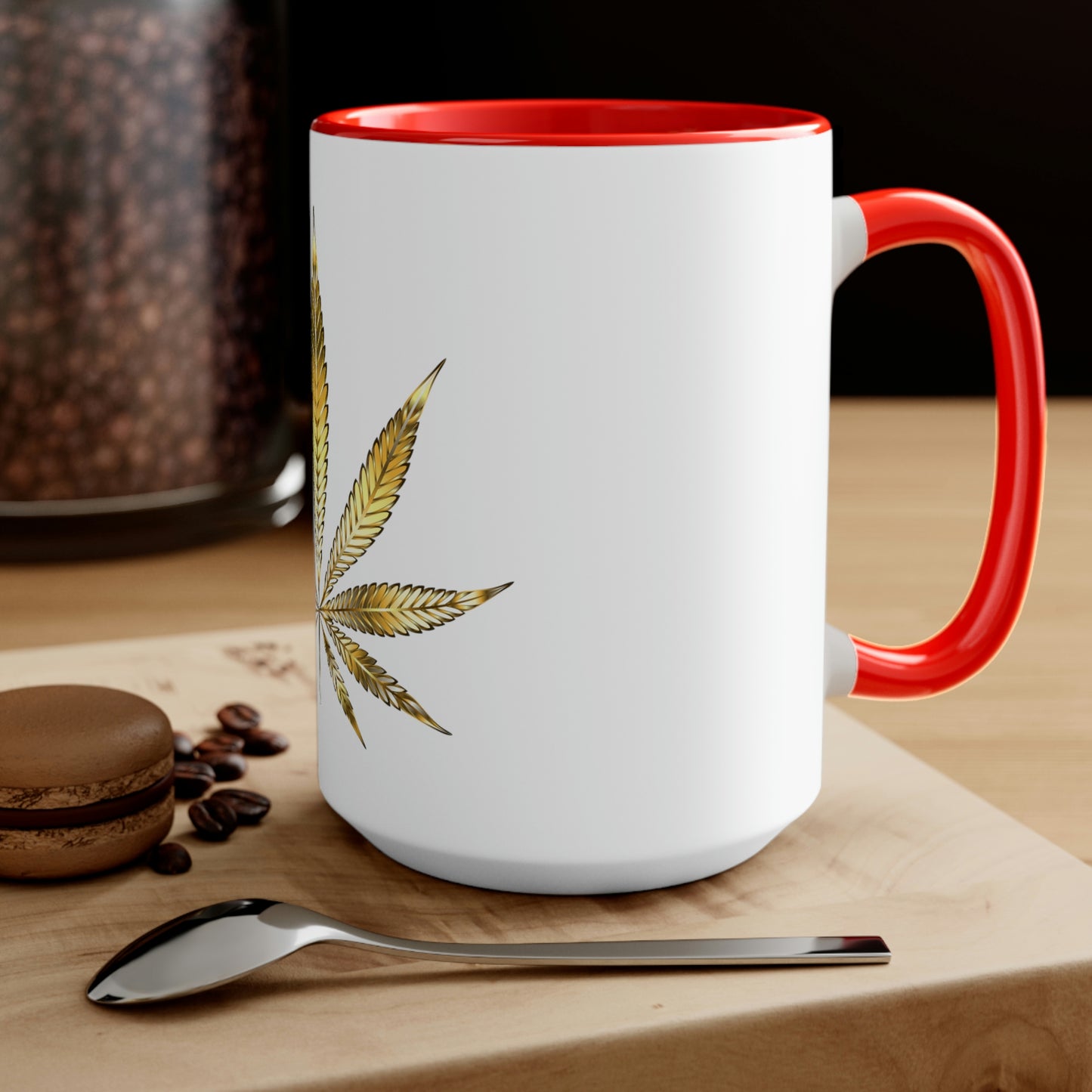 A white cannabis mug with a red interior featuring a bright gold weed leaf on the front center, sitting on a wood base.
