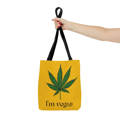 An outstretched hand is holding the I'm Vegan Yellow Ganja Tote Bag for an awesome view