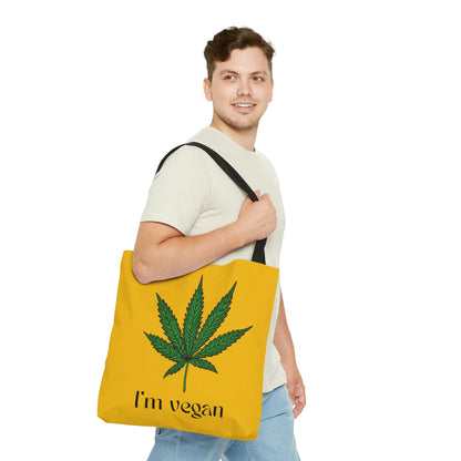 A man is happily grasping the I'm Vegan Yellow Ganja Tote Bag with green weed leaf 