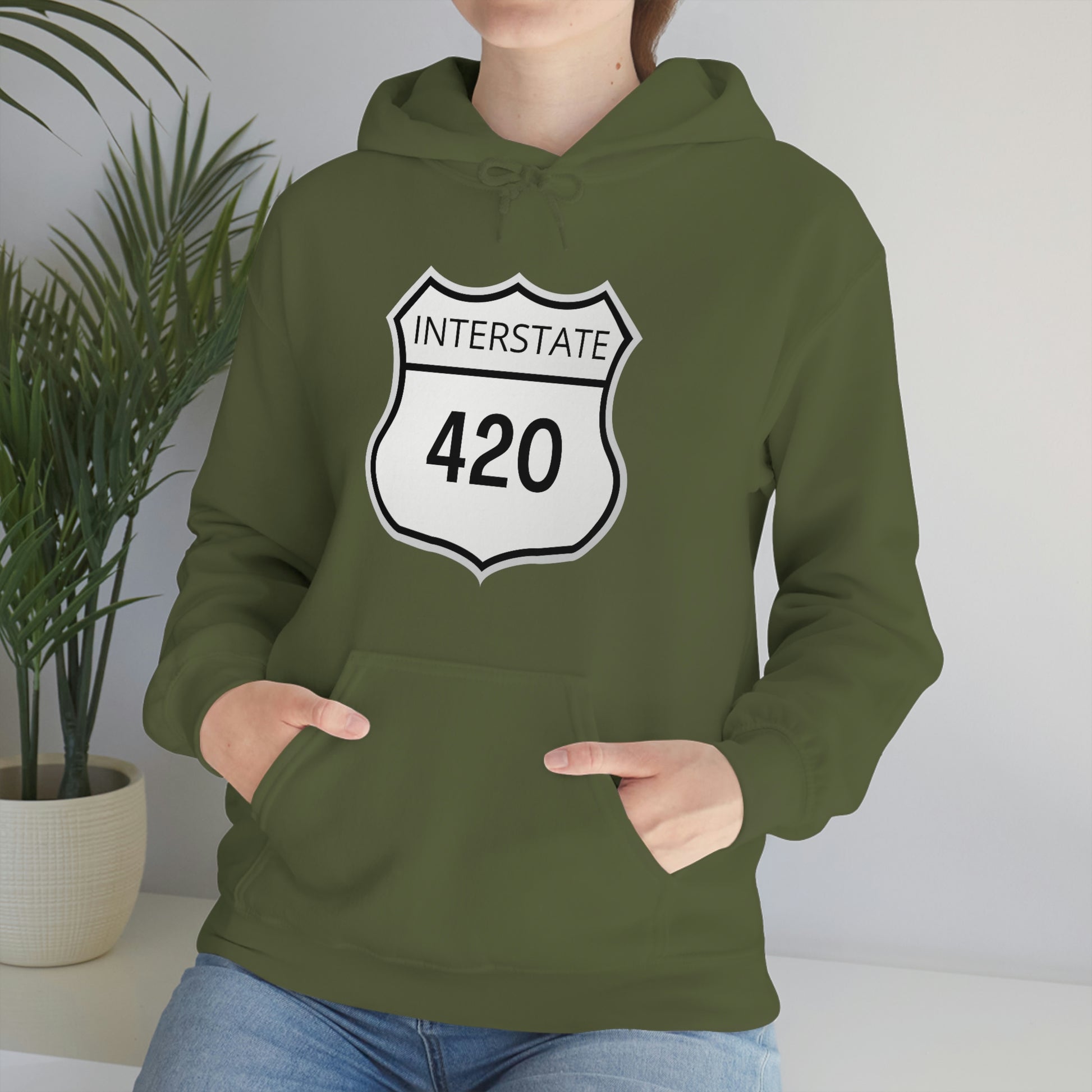 A woman wearing a forest green, Interstate 420, weed hoodie