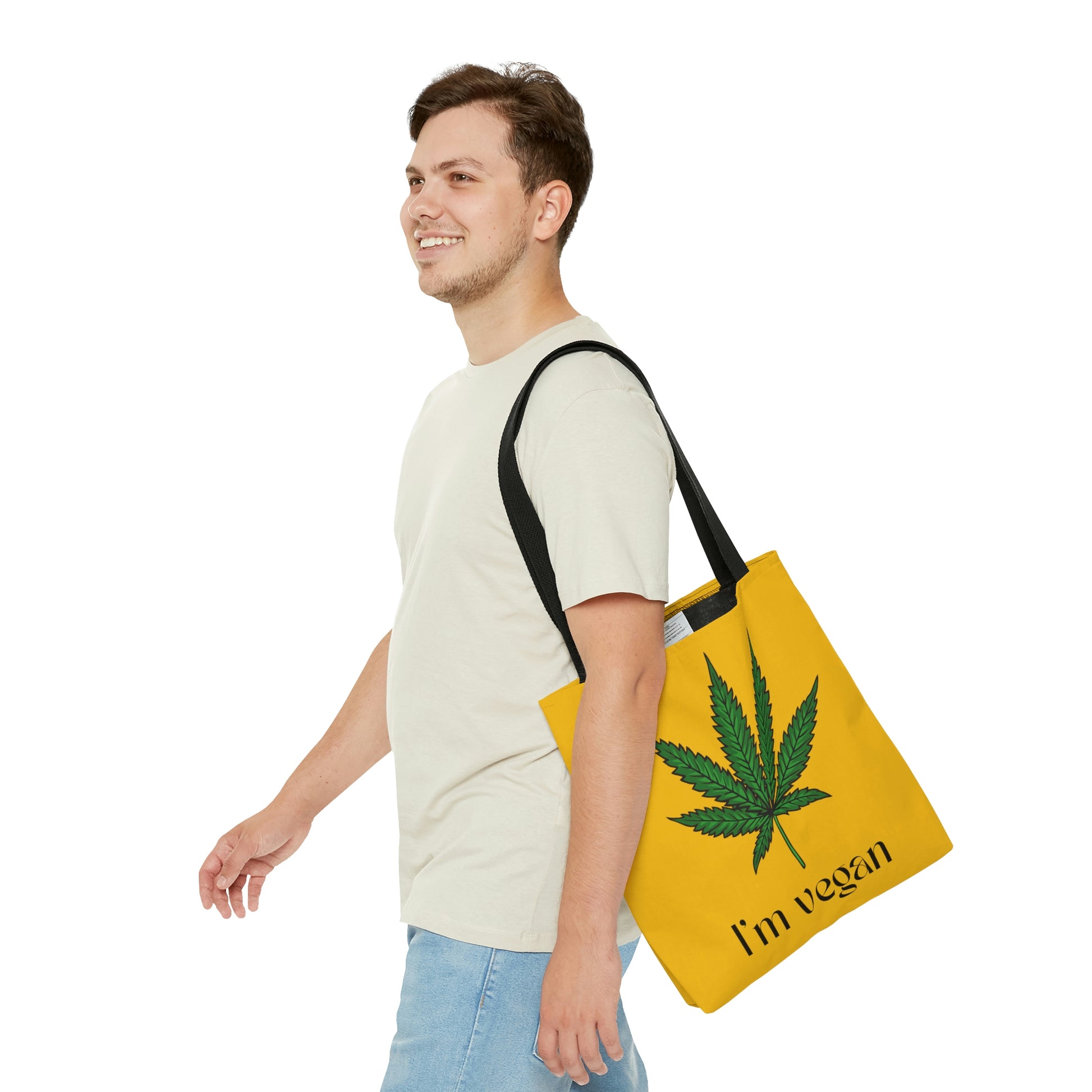 A man handles the I'm Vegan Yellow Ganja Tote Bag with huge green weed leaf  with ease while walking