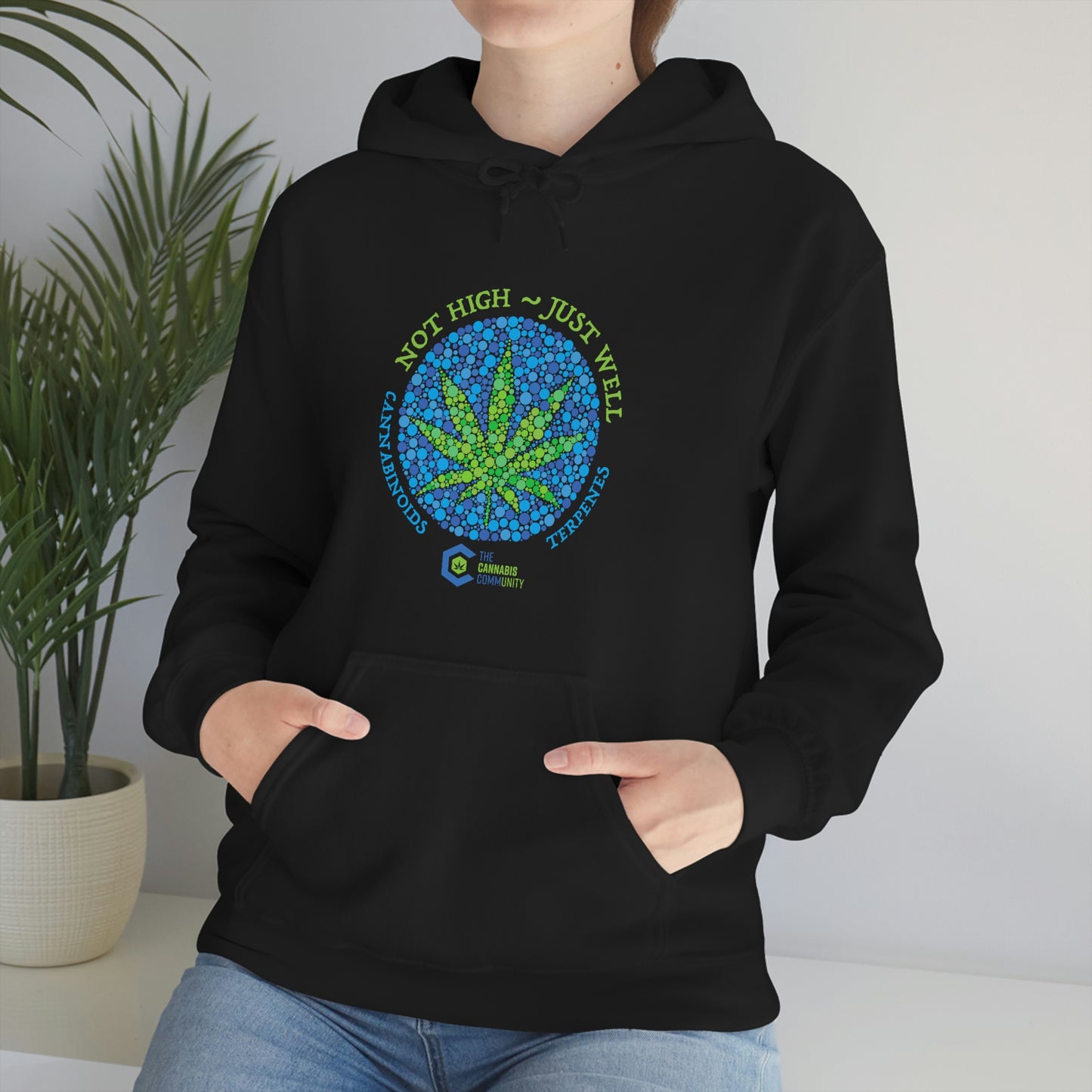 a woman wearing a black Not High, Just Well Cannabis Hoodie with a marijuana leaf on it.