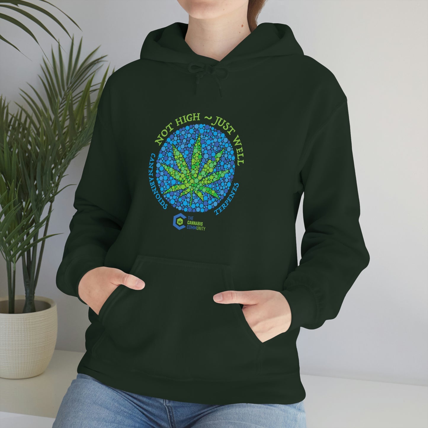 A woman wearing a Not High, Just Well Cannabis Hoodie with a marijuana leaf on it.