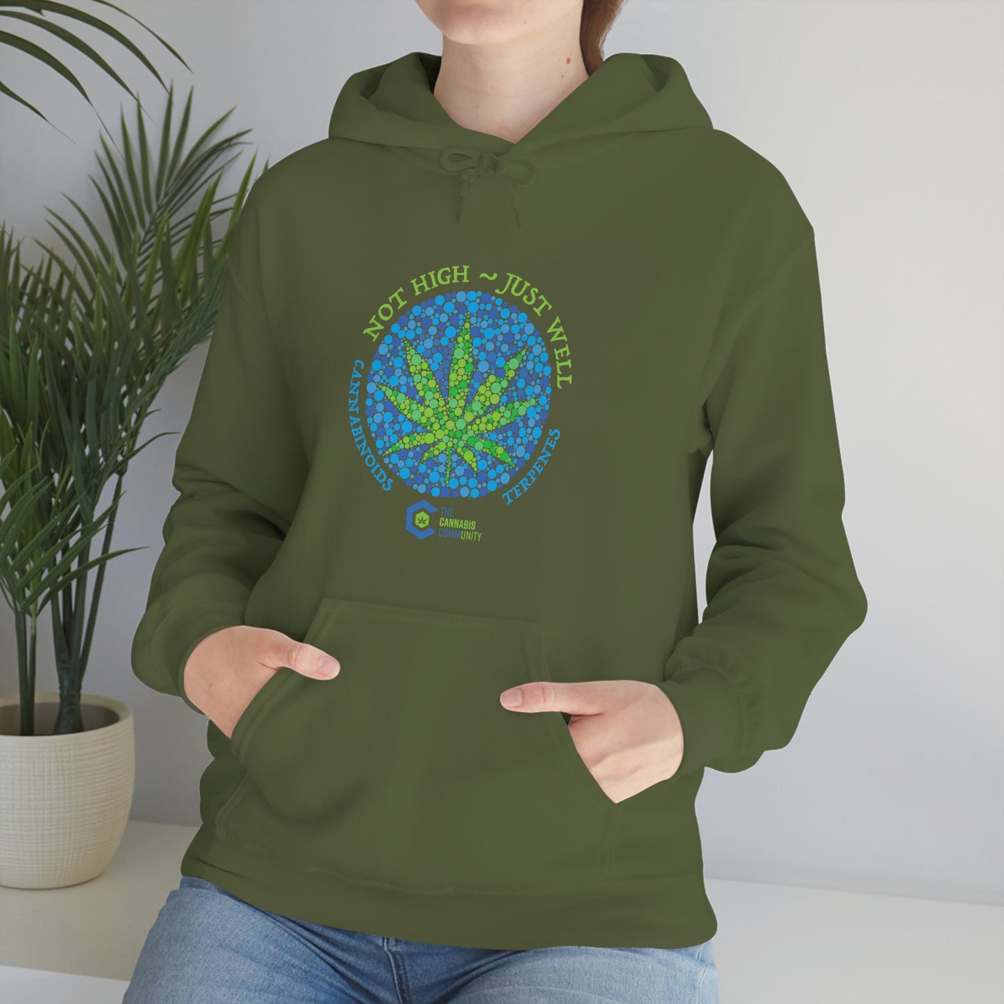 a woman wearing a green Not High, Just Well Cannabis Hoodie with a marijuana leaf on it.