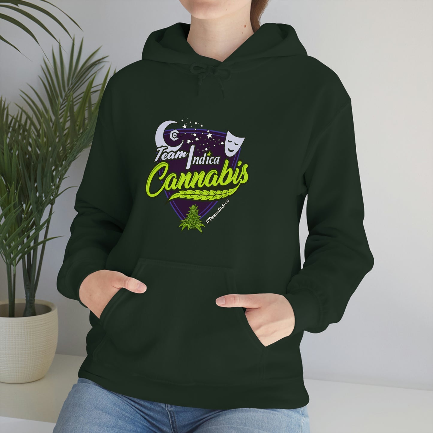 a woman wearing a green hoodie with the word Team Indica Cannabis Pullover on it.