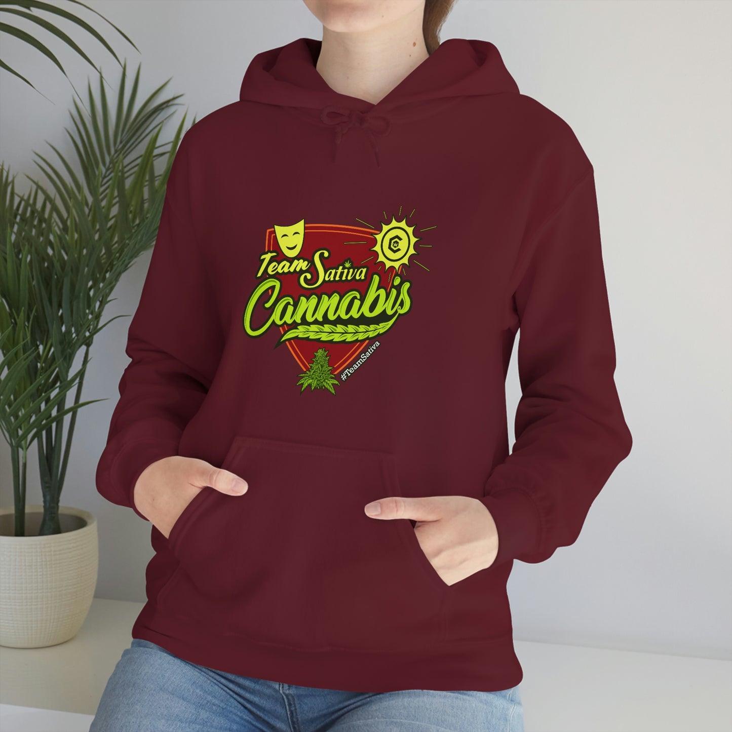 A woman wearing a maroon hoodie with the words Team Sativa Stoner Sweatshirt on it.