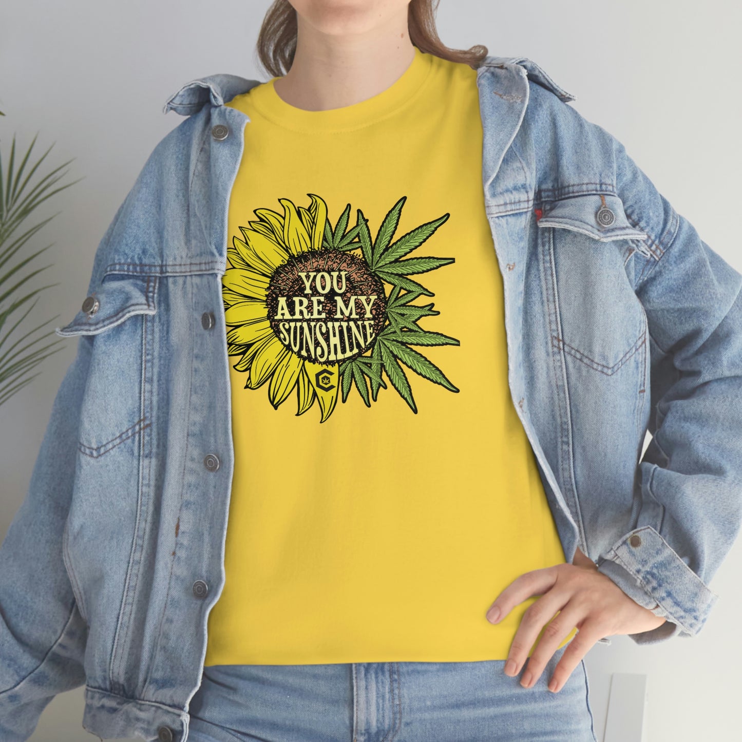 a woman wearing a yellow You Are My Sunshine Weed T-Shirt with sunflowers on it.