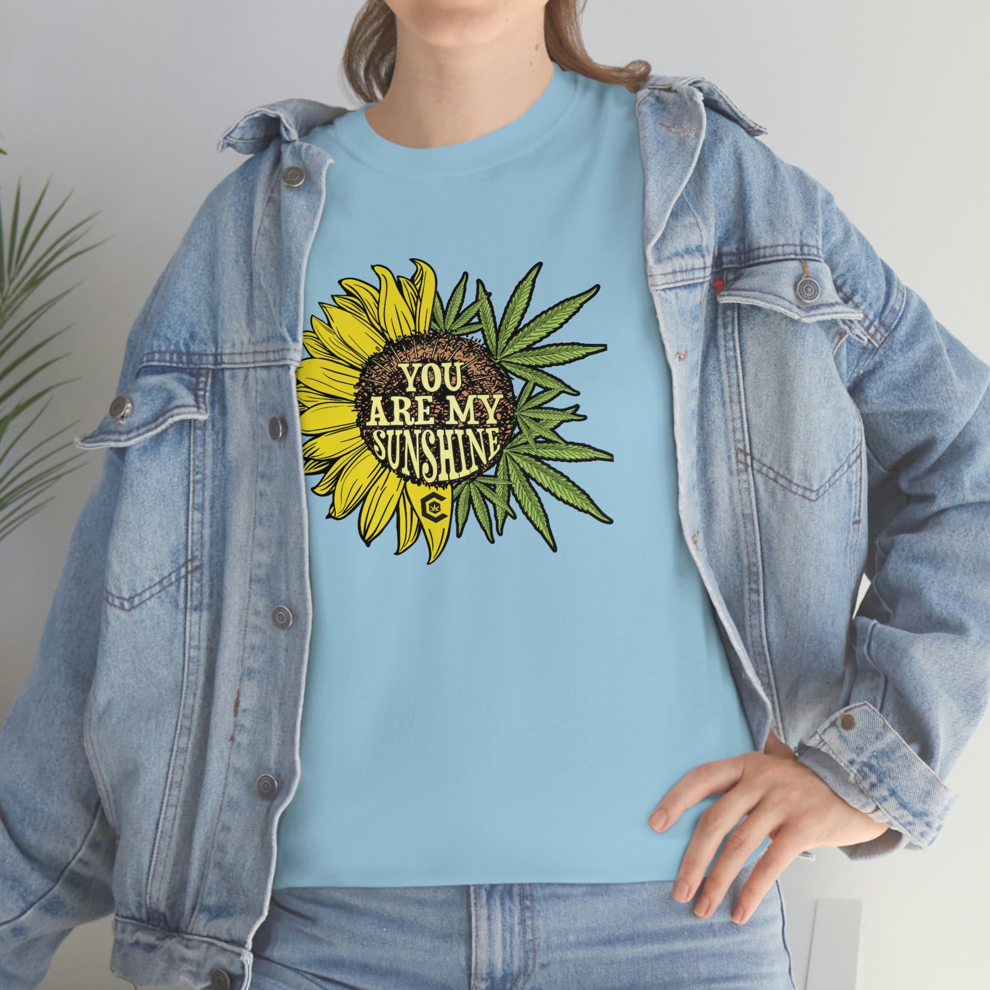 a woman wearing a blue You Are My Sunshine Weed T-Shirt with a sunflower on it.