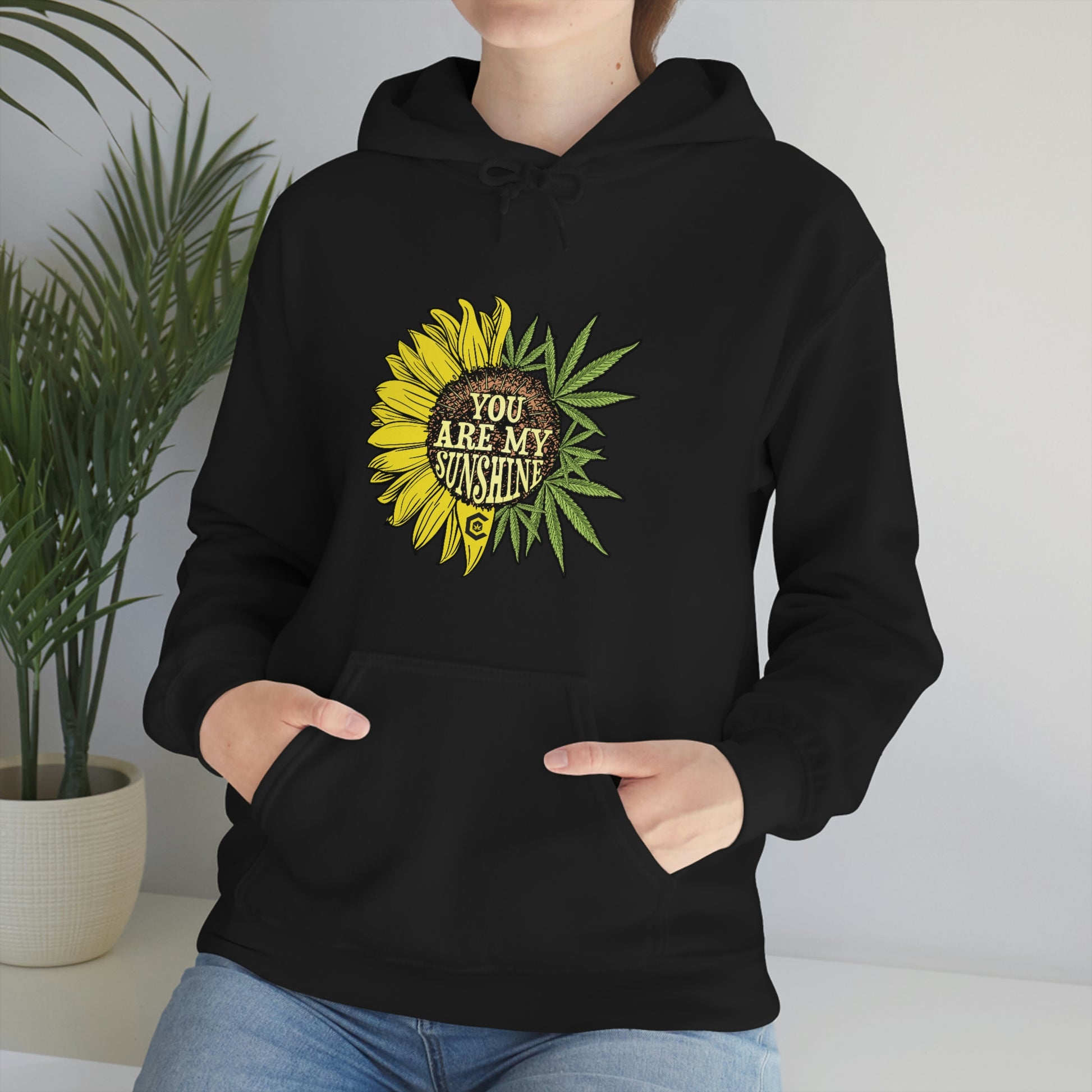 a woman wearing a black You Are My Sunshine Cannabis Sweatshirt with a sunflower on it.