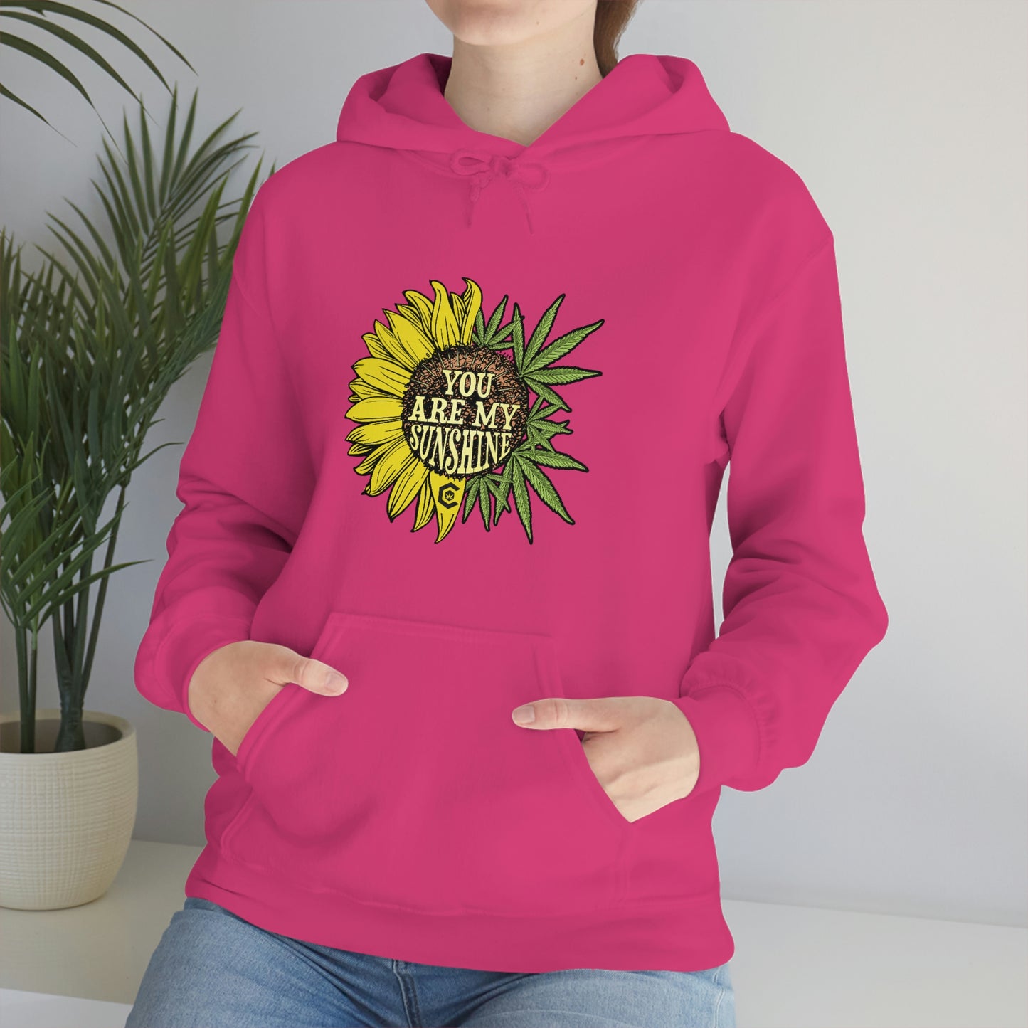 a woman wearing a pink You Are My Sunshine Cannabis Sweatshirt with a sunflower on it.