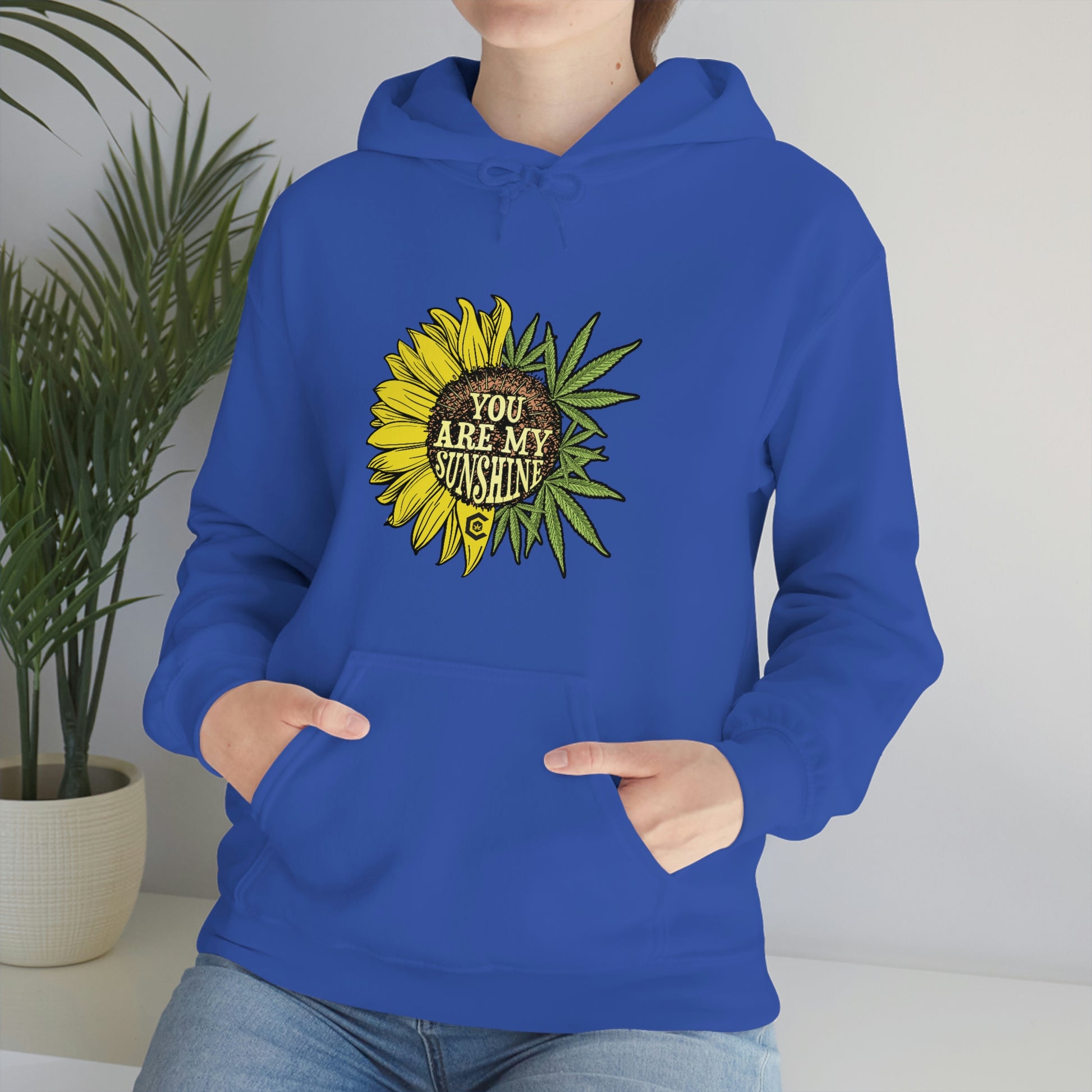 a woman wearing a blue hoodie with the You Are My Sunshine Cannabis Sweatshirt on it.