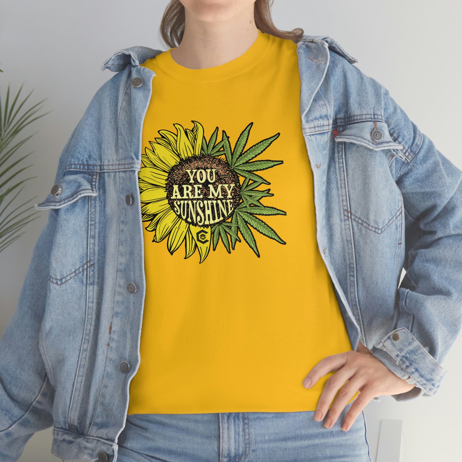 a woman wearing a yellow You Are My Sunshine Weed T-Shirt with sunflowers on it.